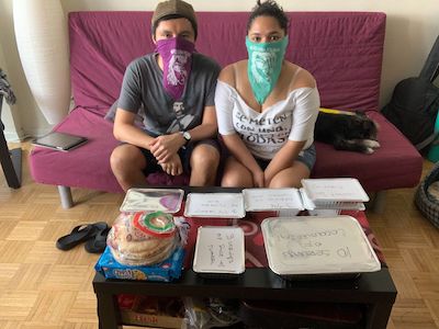 Two volunteers sitting with the meal they have cooked and packaged.