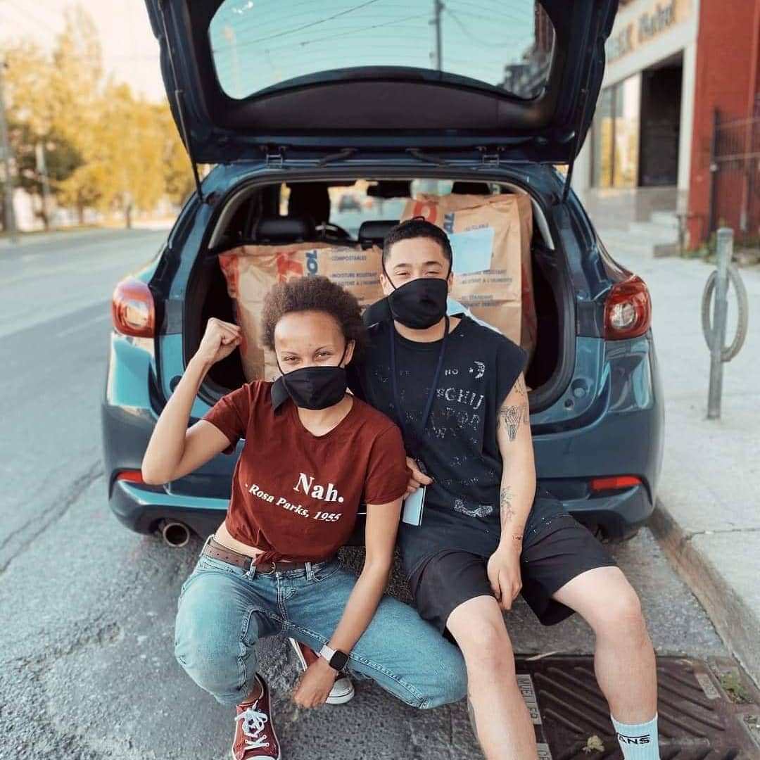 Two of our co-founders sitting in front of a van packed with grocery bundles.