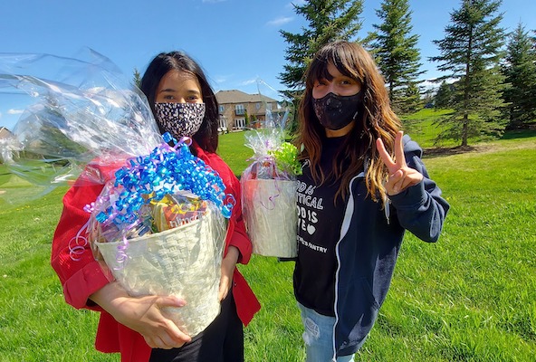 Photo of two organizing volunteers in a grassy field holding gift baskets.
